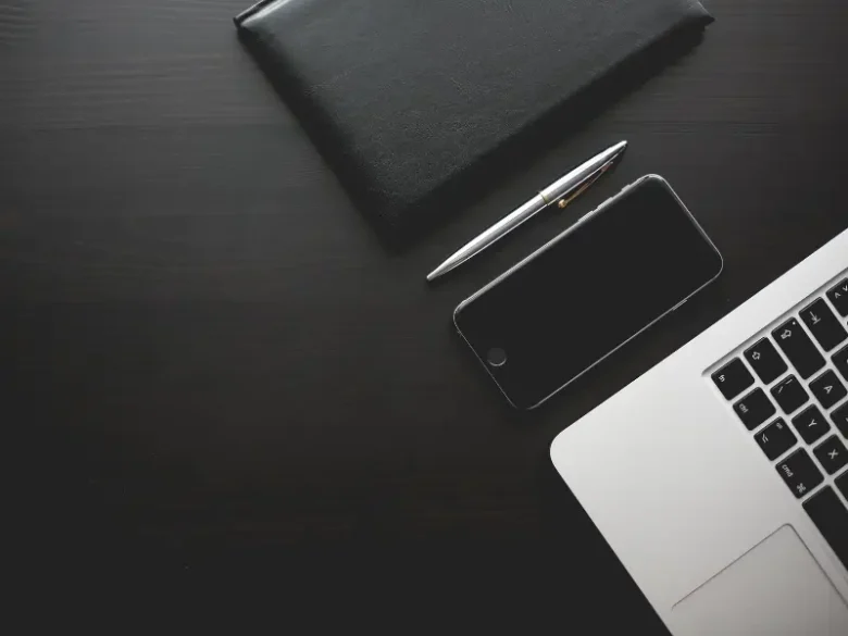 Carteira, caneta, celular e laptops organizados. Como hábitos e disciplina podem melhorar o seu flow no trabalho