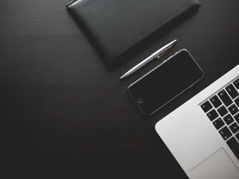 Carteira, caneta, celular e laptops organizados. Como hábitos e disciplina podem melhorar o seu flow no trabalho