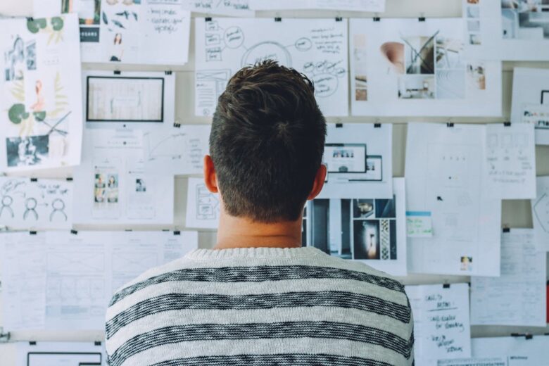 homem olhando mural com ideias representando a importância da experimentação e inovação para melhorar o flow de trabalho
