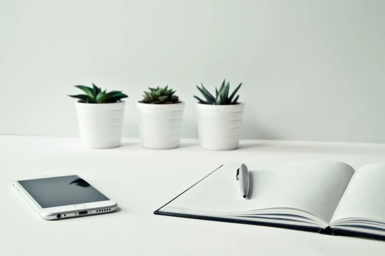 mesa com caderno, celular e decoração, demonstrando a importância do minimalismo para maximizar a produtividade e o estado de flow