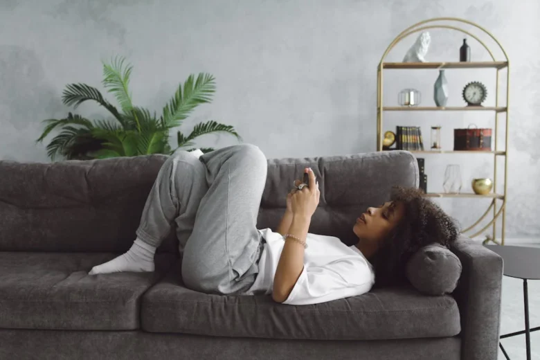 mulher deitada no sofá usando o celular, mostrando como a procastinação pode arruinar a produtividade e o flow